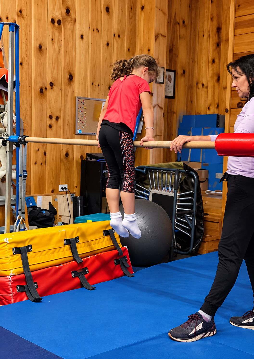 Mrs. Kathy coaching a child on the gymnastics bar