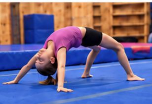 A young gymnast practicing a bridge on the blue gym floor