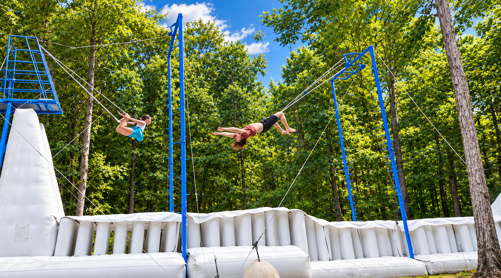 Two athletes practicing on the outdoor trapeze rig