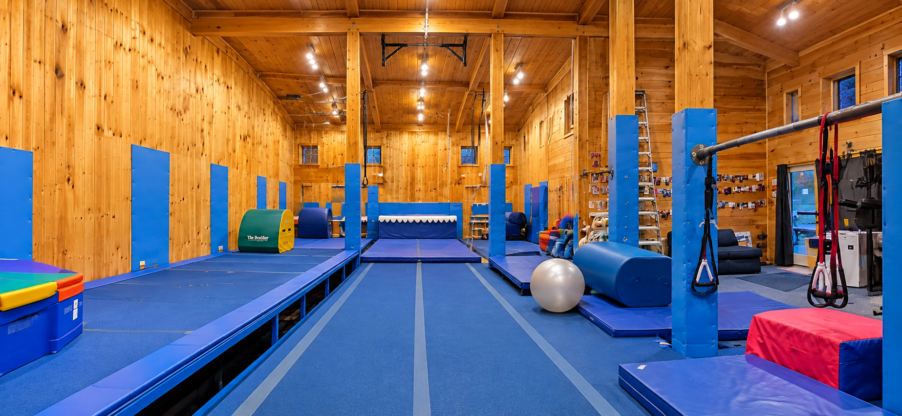Full view of the indoor gym with blue tumbling lanes and wood walls